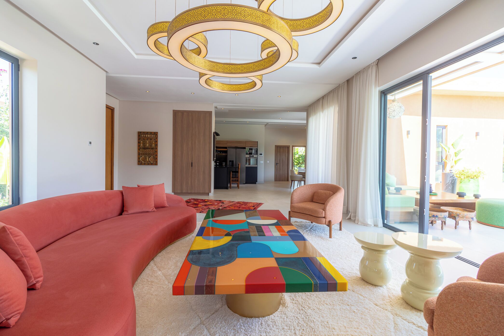 Ein modernes Wohnzimmer mit einem großen Sofa, einem bunten Couchtisch und einer Deckenleuchte.