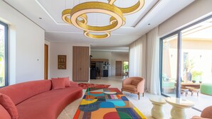A modern living room with a large sofa, a colorful coffee table, and a chandelier. - Villa Jamila Marrakech - Authentic luxury and heated private pool. (Marrakech)