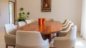 A round wooden table surrounded by six upholstered chairs with a potted plant on the left. - Villa Jamila Marrakech - Authentic luxury and heated private pool. (Marrakech)