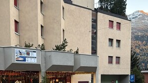 A building with a ground-floor restaurant named 'DADOURA' and a parking sign. - Studio in the center, with pool and sauna, 400 mt from the ski lifts (Sankt Moritz)