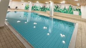 An indoor swimming pool with wooden ceiling beams, tiled floor, and a mural of plants on the wall. - Studio in the center, with pool and sauna, 400 mt from the ski lifts (Sankt Moritz)