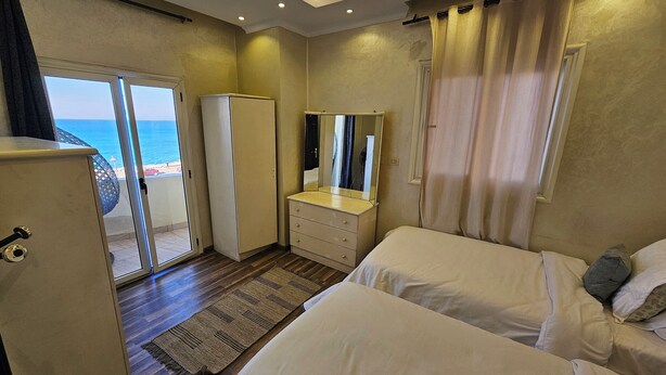 A bedroom with two beds, a dresser, a mirror, and a wardrobe. - Simple sea view (families only) (Alexandria)