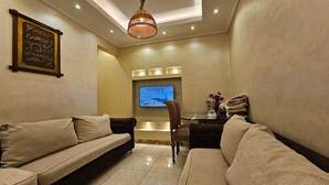 A modern living room with two sofas, a TV, and a decorative vase. - Simple sea view (families only) (Alexandria)