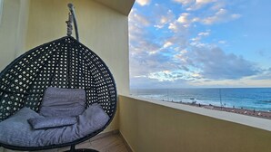 A balcony with a hanging chair, a view of the sea, and a paved walkway. - Simple sea view (families only) (Alexandria)