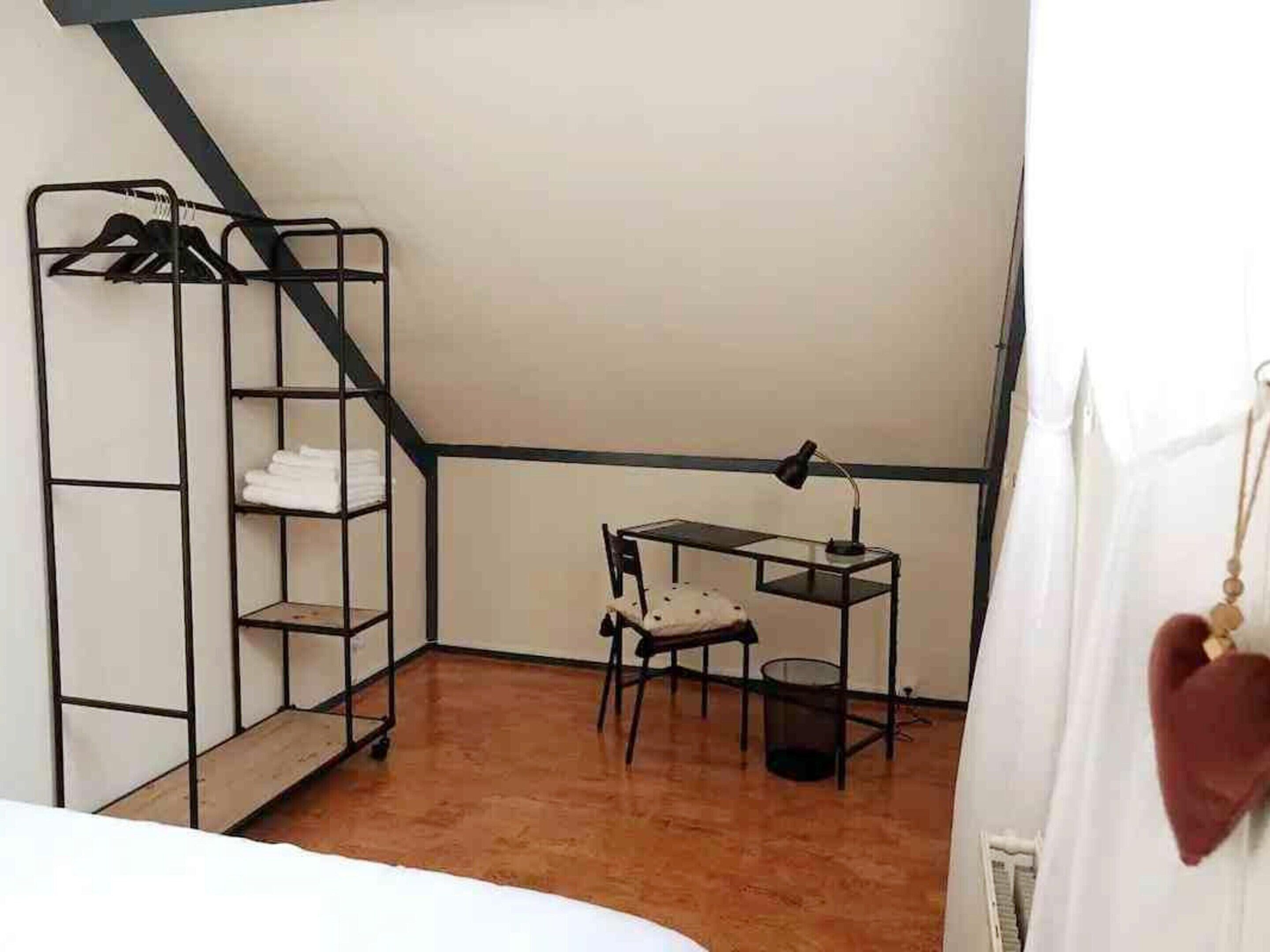 Et værelse med køjeseng, et skrivebord med stol, en lampe og en hjerteformet pynt.