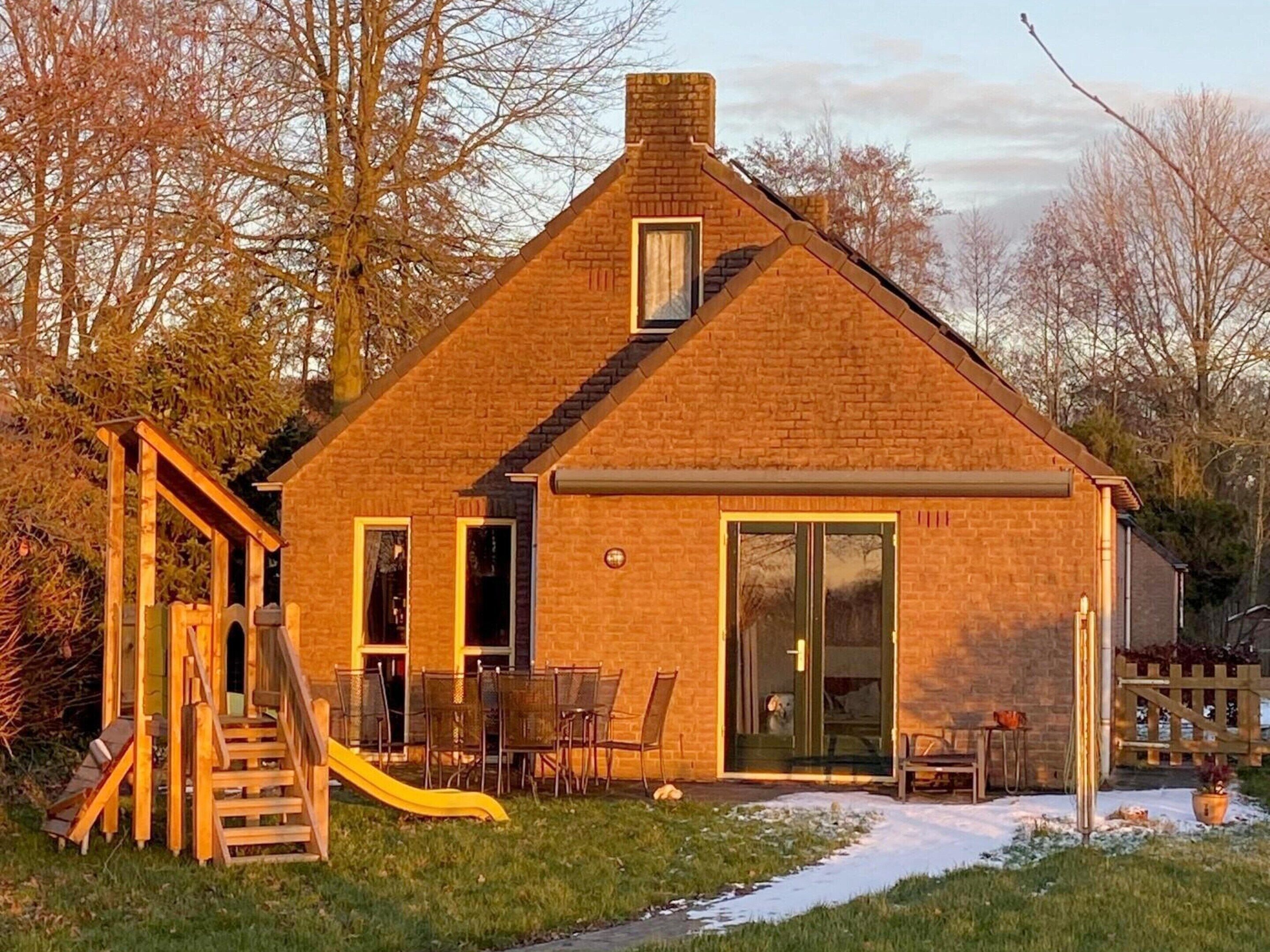 A brick house with a chimney, a sliding door, and a small patio area with outdoor furniture.