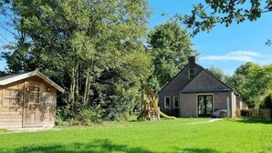 A house with a large yard, a wooden playhouse, and a slide. - Family Bungalow With Private Garden (Ewijk)