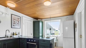 Une cuisine moderne avec des meubles de couleur sombre, un four encastré et une grande fenêtre offrant une vue sur l’extérieur.
