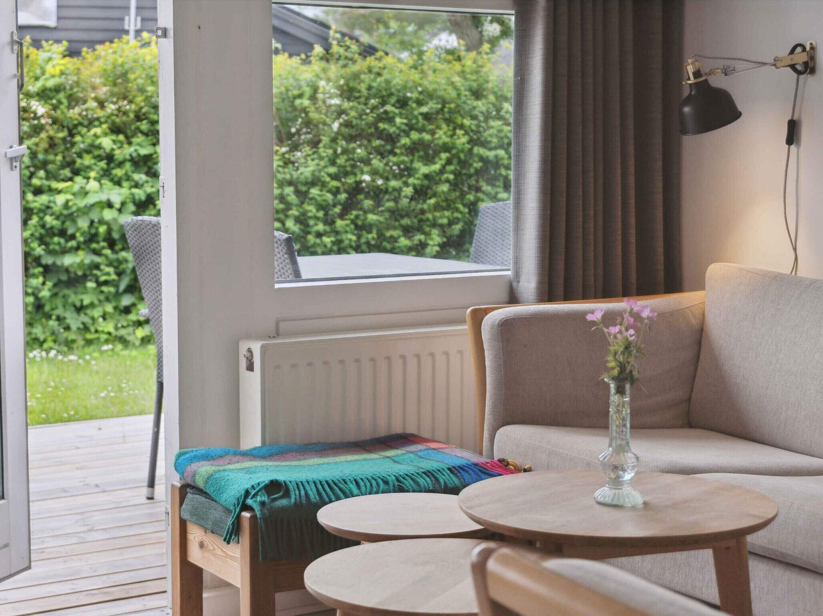 A cozy room with a sofa, a small table, and a window overlooking a garden.