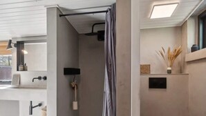 A modern bathroom with a shower, a toilet, a sink, and a mirror.