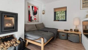 A cozy room with a bed, a fireplace, a window, and a wall-mounted artwork.