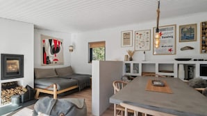 A modern living room with a fireplace, a sofa, a dining table, and a kitchen area.