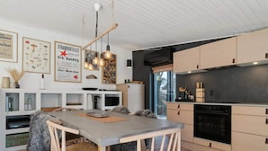 A modern kitchen with wooden cabinets, a built-in oven, and a dining area with a table and chairs.