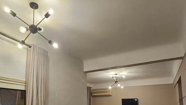 Een moderne woonkamer met een ronde fauteuil, twee banken, een salontafel en een plafondlamp.