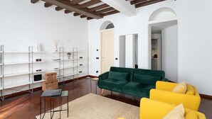 A modern living room with a green sofa, yellow armchairs, and white shelving units. - Spacious Flat W/wooden Beams - Porta Venezia (Milan)