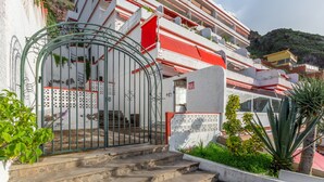 A building with a gated entrance, steps leading up to a door, and a balcony with red awnings. - Vacation Home 'Crisol' with Sea View, Private Terrace and Wi-Fi (Mesa del Mar)
