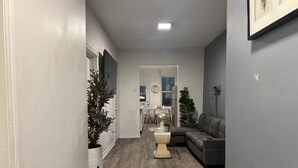 Ein Flur mit einer grauen Couch, einem Blumentopf und einer dekorativen Steinskulptur.