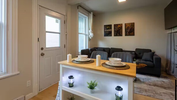 A modern living room with a sofa set, a wooden coffee table with decorative items, and a wall with framed artwork. - Confortable Home on Notre Dame & near Downtown (Montreal)