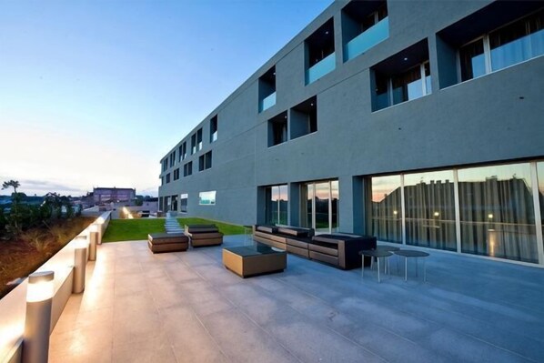 A modern building with a flat roof, large windows, and outdoor seating areas. - Villa C Boutique Hotel (Azurara)