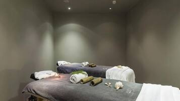 A spa room with two beds, towels, and spa products.