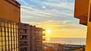 Un edificio moderno con fachada de vidrio y vista al atardecer sobre el océano.