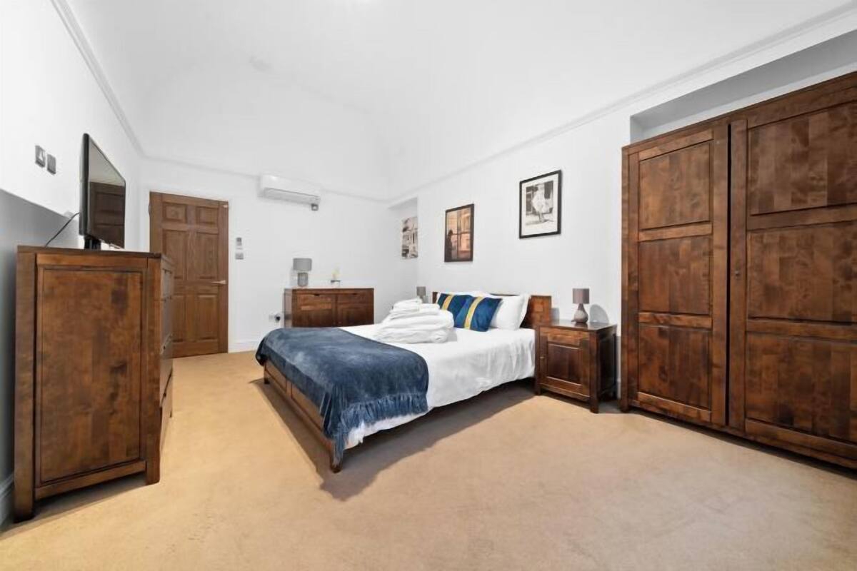 A bedroom with a bed, wooden wardrobe, and a television.