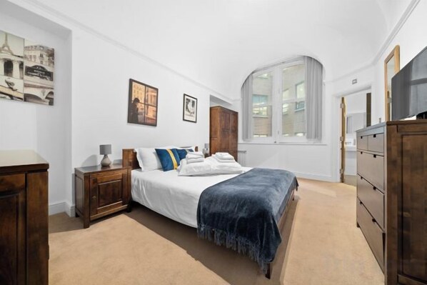 A bedroom with a bed, a dresser, a nightstand, and a window. - Apartment 2, 48 Bishopsgate by City Living London (London)