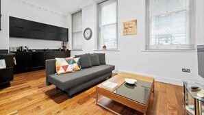 Un salon moderne avec un canapé, une table basse et un coin cuisine à l’arrière-plan.