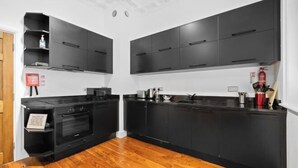 Une cuisine moderne avec des meubles de rangement noirs, un four encastré et un plancher en bois.