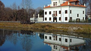 A white building with a red roof, a reflection in the water, and statues in front. - Villa Veneta Ca' Sabbioni  (Mestre)