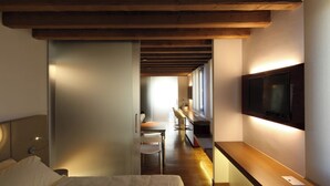 A modern hotel room with a bed, a desk, a chair, a TV mounted on the wall, and a wooden ceiling. - Villa Veneta Ca' Sabbioni  (Mestre)