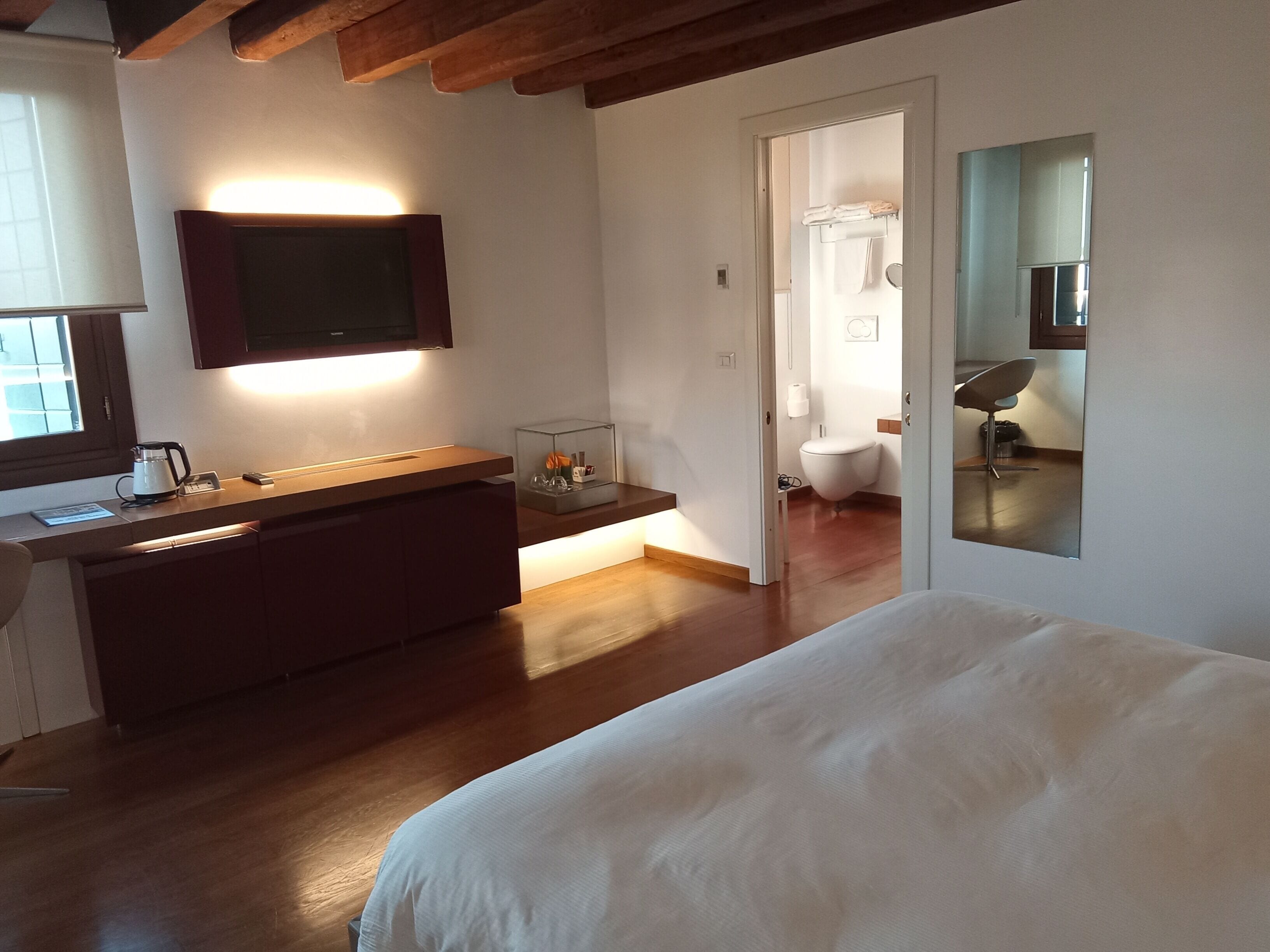 Ein Schlafzimmer mit einem Bett, einem Nachttisch, einem Spiegel und Blick ins Badezimmer.
