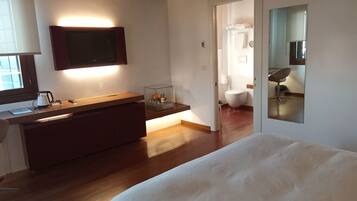 Ein Schlafzimmer mit einem Bett, einem Nachttisch, einem Spiegel und Blick ins Badezimmer.
