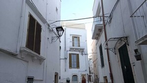 Eine enge Kopfsteinpflasterstraße, gesäumt von weißen Gebäuden mit Balkonen und Fensterläden.