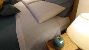 Ein Schlafzimmer mit Bett, Kissen, einer Lampe und einem Nachttisch.