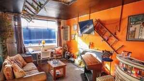Un salon confortable avec un canapé, des fauteuils, une table basse, un piano et un radiateur.