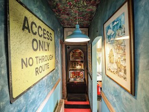 A hallway with a sign reading 'ACCESS ONLY NO THROUGH ROUTE' and a vintage arcade machine. - Dormy Cottage (Skegness)