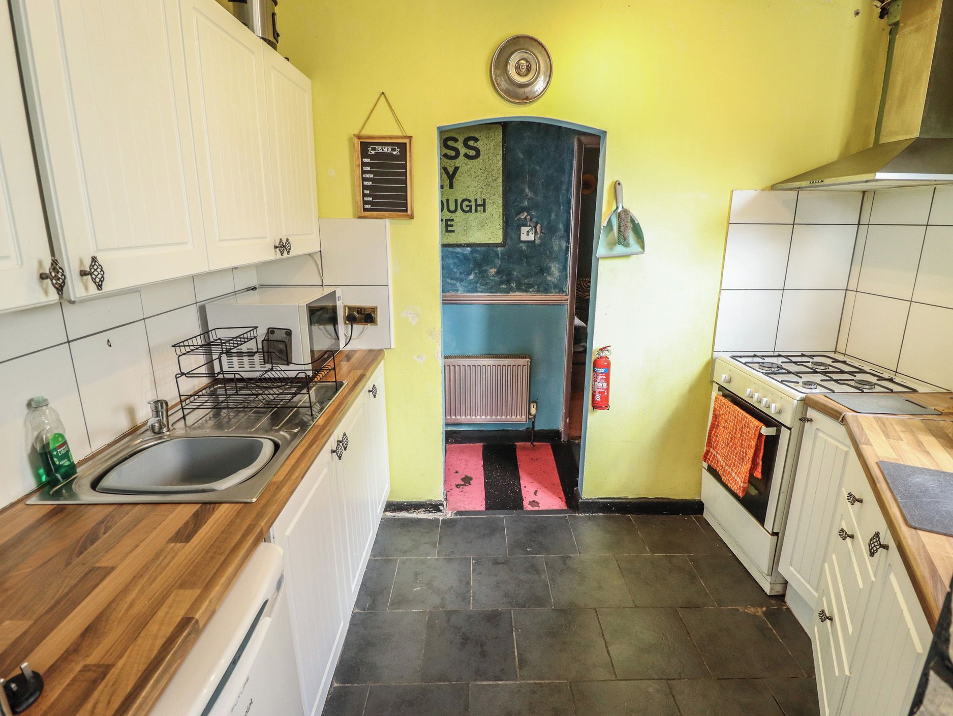 A kitchen with white cabinets, a gas stove, a sink, and a blue wall with a sign.