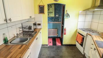 A kitchen with white cabinets, a gas stove, a sink, and a blue wall with a sign.