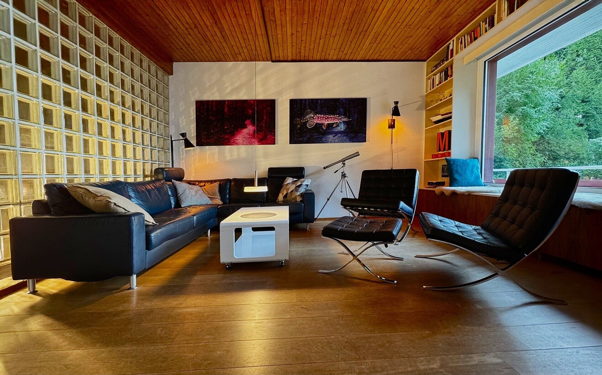 Un salon moderne comprenant un canapé, une table basse, un fauteuil, un télescope et une bibliothèque.