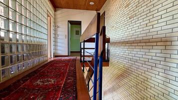 Un couloir avec un tapis rouge à motifs, un plafond en bois et des murs en briques.