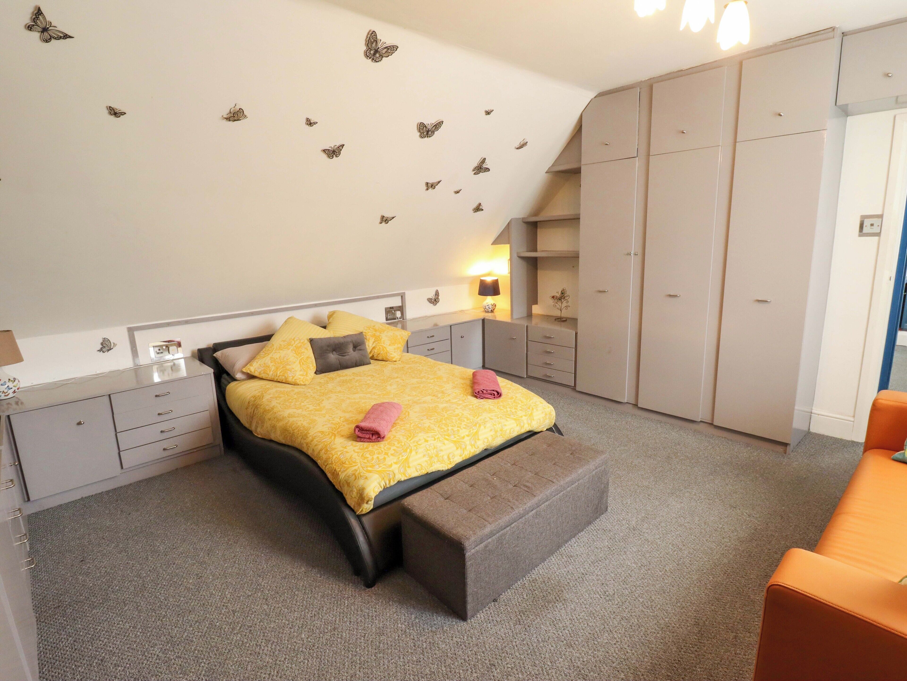 A bedroom with a bed, bedside tables, a wardrobe, and a bench.
