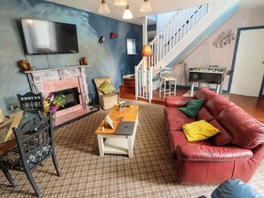 A living room with a fireplace, a sofa, a coffee table, a TV, and a staircase. - Peartree Cottage (Skegness)