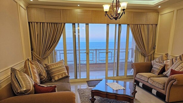 Una sala de estar con dos sofás, una mesa de centro y vista al mar a través de amplios ventanales.
