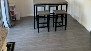 Et spiseområde med et træbord og bænke, en lysekrone og en hvid væg.