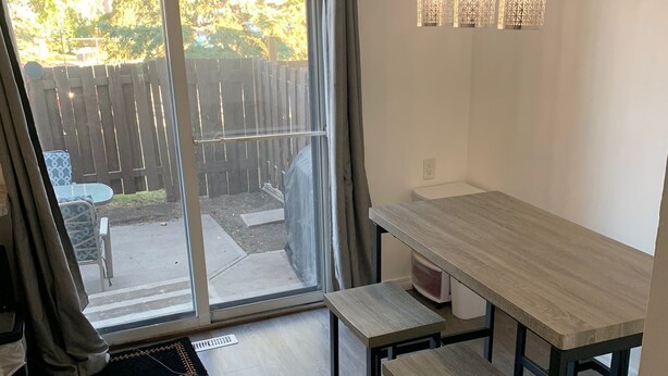 Et moderne køkken med et træbord og bænk, en skydedør til en patio, og hængende lamper over bordet.