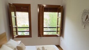 A bedroom with a bed, two windows, and a decorative wall piece.
