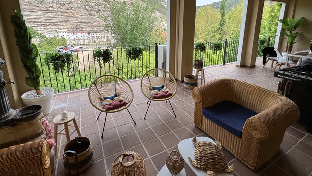 A balcony with wicker furniture, a sofa, and potted plants.