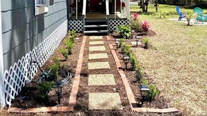 A house with a red door, a porch, and a garden with stepping stones leading to the entrance. - The Little Sandpiper - Charming Port Royal Cottage (Port Royal)