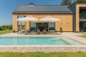 A modern house with a swimming pool, outdoor seating, and a large TV screen. - Blacksmith House - Stylish vacation home with spa & nature views (Varaždinske Toplice)